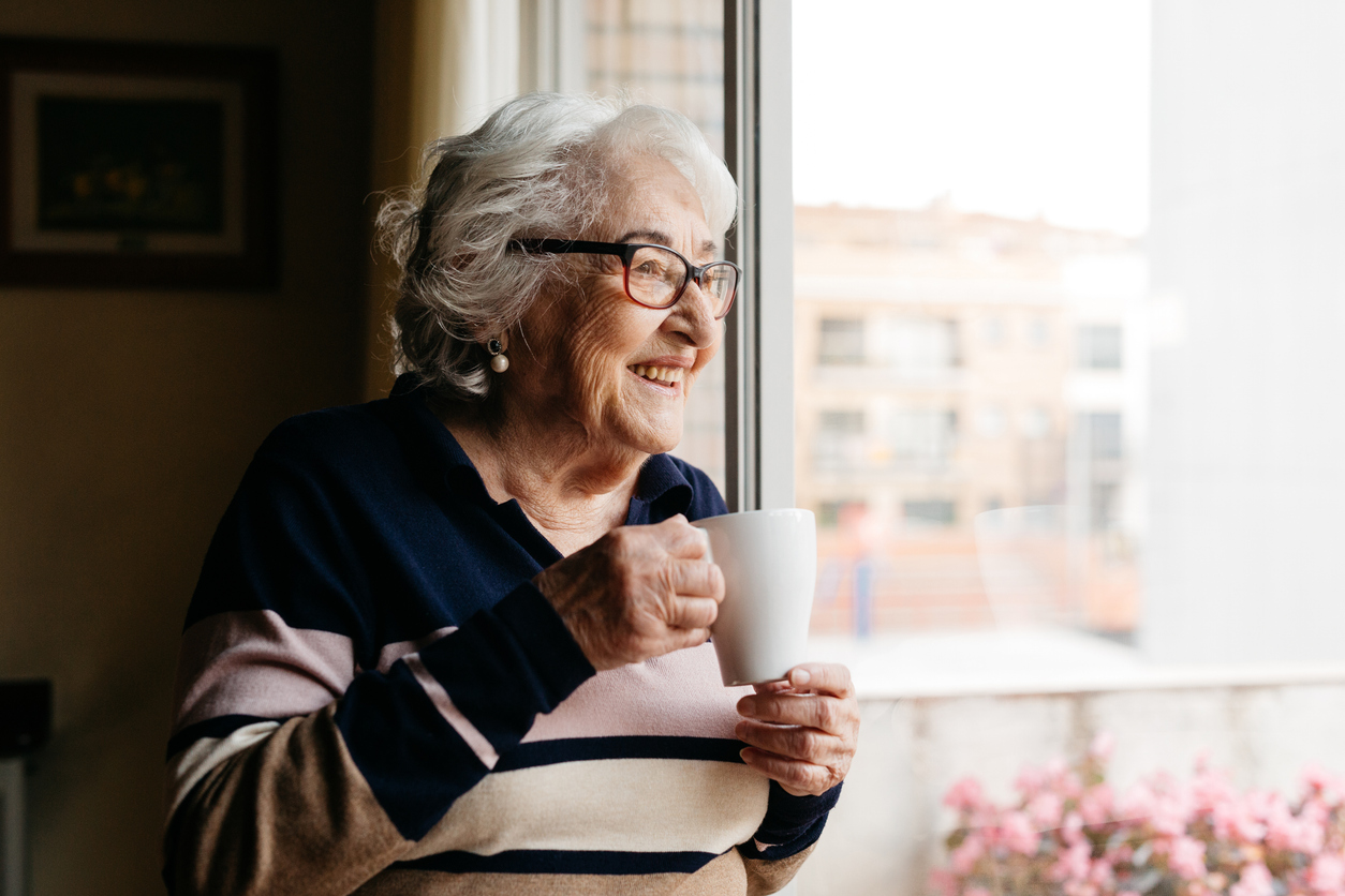 Elderly woman drinking coffe at home.